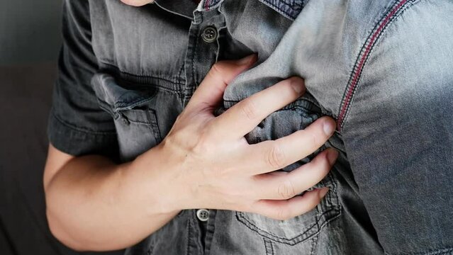 Man is sick and in pain and uses his hands to squeeze his chest He had chest pain caused by an acute heart attack. medical and health concepts