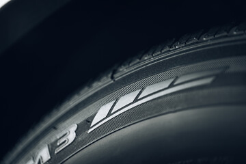 Closeup of the tread of a summer car tire on a sunny day. tires against black. fuel efficient car tires. - obrazy, fototapety, plakaty