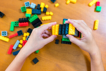 children's toy constructor Focus on a specific point
Closeup of children's hands playing with many colorful plastic blocks. Children have fun building robots. Relaxation created with modern techniques