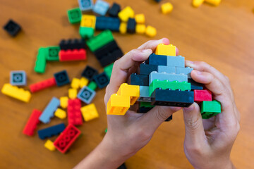 children's toy constructor Focus on a specific point
Closeup of children's hands playing with many colorful plastic blocks. Children have fun building robots. Relaxation created with modern techniques