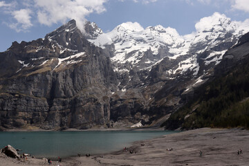 Obraz premium Snow Covered Black Rock Mountain Near Lake and Dark Coast in Kandersteg 