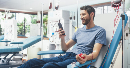 Caucasian Man Donating Blood For People In Need In Hospital. Male Donor Squeezing Heart-Shaped Red...