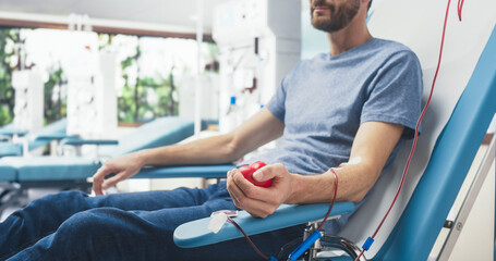 Close Up Shot Of Hand Of Male Blood Donor With an Attached Catheter. Caucasian Man Squeezing...