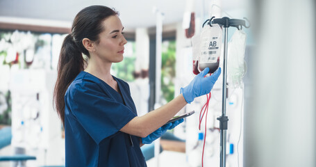 Female Nurse Holding Tablet Computer And Checking The Blood Bag In Donation Center. Professional...