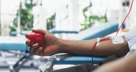 Close Up Shot Of Hand Of Male Blood Donor With an Attached Catheter. Black Man Holding Heart-Shaped...