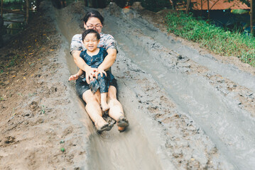 Asian happy mother and child have activities together on holidays. Mom and her son playing slider...