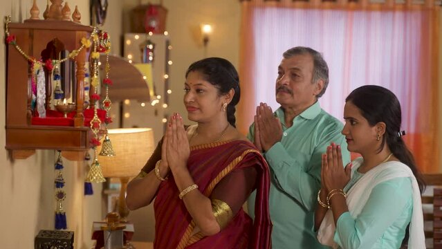 Indian middle class family praying to god during diwali festival celebration in front mandapam - concept of traditional custom, special ceremony and sacred customs