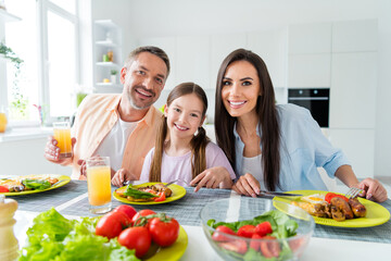 Photo of cheerful charming married couple small daughter enjoying delicious supper indoors home kitchen