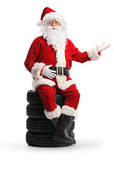 Santa claus sitting on a pile of tires and showing with hand