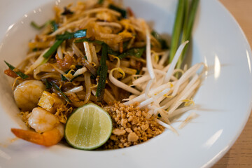 Pad Thai with shrimp, sprouts and green onions on white dish