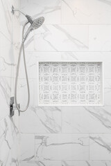 A luxury shower detail with large marble tiles, polished chrome showerhead with hose, and a niche with mosaic pattern tiles. - obrazy, fototapety, plakaty