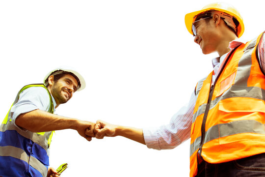 Two engineers success : Caucasian male architect worker and asian engineer  worker bumping fists working colleagues in team believing positive approach in industrial business project planning.