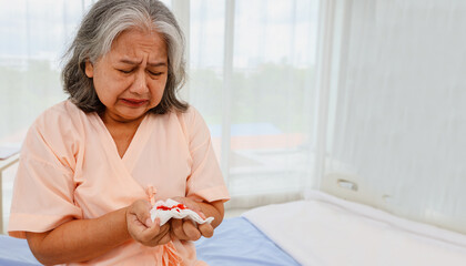 Elderly asian woman stressed, cry worry sitting on a bed hospital emergency room suffering from...