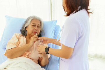Female doctor takes care elderly female patients with friendliness drink clean refreshing water willingness make the patients feel good giving encouragement recuperate their illnesses in the hospital.