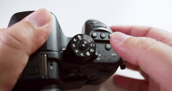Turning the dial and pressing the buttons of the camera to adjust the settings before taking a photograph.