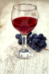 Glass with red wine and a bunch of grapes in the garden. Red wine in a glass and a bunch of grapes.