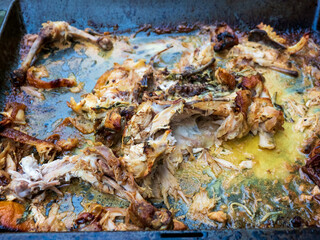 Obraz na płótnie Canvas roasted chicken on a metal tray after eating the meat leftover skin bones and cold congealed fats