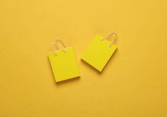 Miniature yellow shopping bags on yellow background. Black Friday, world shopping day, sale