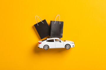 Toy car with Miniature black shopping bags on a yellow background. Black Friday, world shopping...