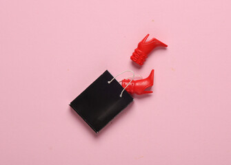 Shopping bag with doll boots on a pink background. Minimalism shopping, sale concept