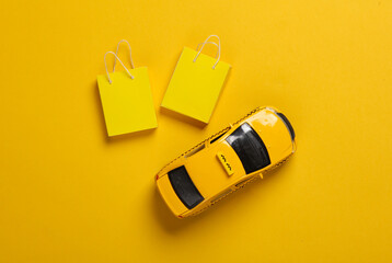 Toy taxi car with Miniature shopping bags on a yellow background. Black Friday, world shopping day,...