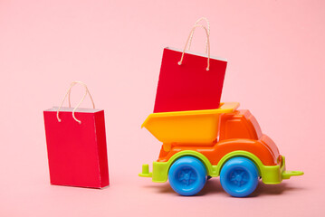 Toy dump truck with shopping bags on a pink background