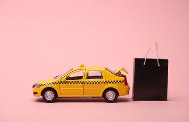 Toy taxi car and Miniature shopping bags on a pink background. Travel and shopping concept