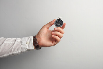 Man's hand in white shirt holds paper compass on gray background. Business concapt