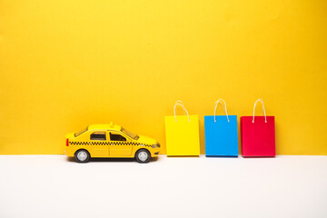 Toy taxi car with Miniature paper shopping bags on yellow gray background. Black Friday, world...