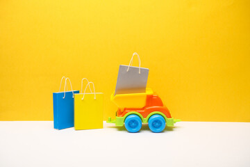 Toy dump truck with shopping bags on yellow gray background