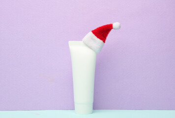 Cream tube with santa hat on pastel background