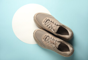 Beige sneakers on a white circles. Blue background. Creative idea. Fashion concept. Top view
