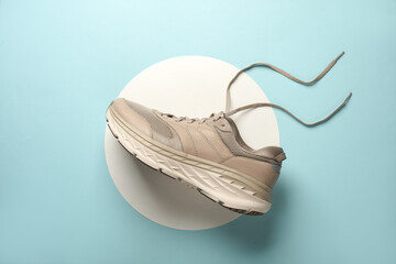 Beige sneaker on a white circles. Blue background. Creative idea. Fashion concept. Top view