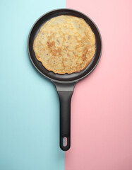 Frying pan with pancakes on pink blue background. Top view