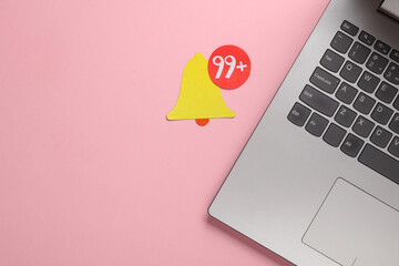 Paper cut notification bell icon and laptop on pink background