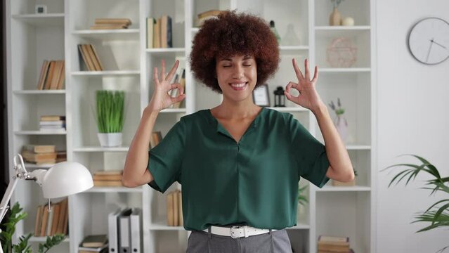 Smiling Young adult entrepreneur freelance black woman small business owner showing ok sign in office with both hands
