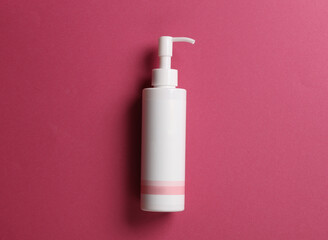 White lotion dispenser bottle on pink background