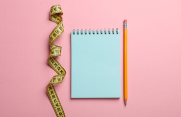 measuring tape and notebook with pencil on pink background. Weight loss, diet concept