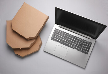Laptop and cardboard craft pizza boxes on gray background. Top view
