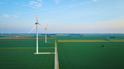 Early morning aerial wind farm in lush green farmland with soft pink skies © Nicholas J. Klein