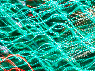 Wavy light trails of LED lights in an ornamental urban garden decorated for holiday celebration at night. Long exposure with motion blur. Light painting.