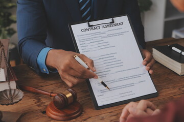 Justice and Law concept. Legal counsel presents to the client a signed contract with gavel and...
