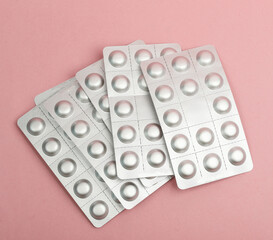 Metal blisters of pills on pink background