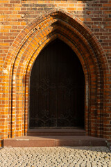 An antique wooden gate with forged metal patterns framed by brickwork