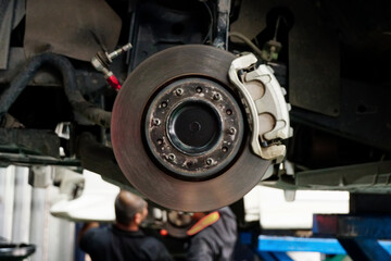 A disc brake of use car in garage with man auto mechanic on background for maintenance , checking, repairing or service concept.