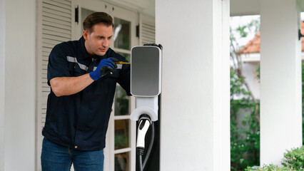 Qualified technician install home EV charging station, providing maintenance service for electric...