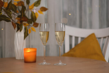 autumn home decoration. Two glasses of champang, vase autumn yellow leafes,candle on round wooden table.