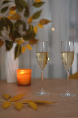 autumn home decoration. Two glasses of champang, vase autumn yellow leafes,candle on round wooden table.