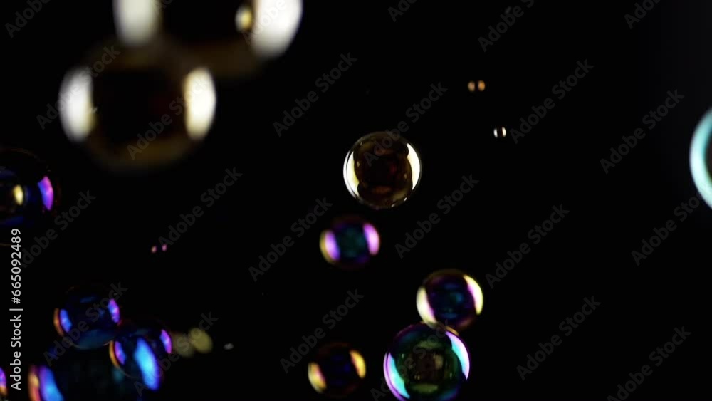 Poster colorful soap bubbles fly in empty space on isolated black background. colorful lights. many rainbow