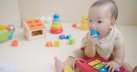 Portrait Of Adorable Happy little Asian baby child Toddler playing with colorful toy on floor living room, Educational game for baby and toddler